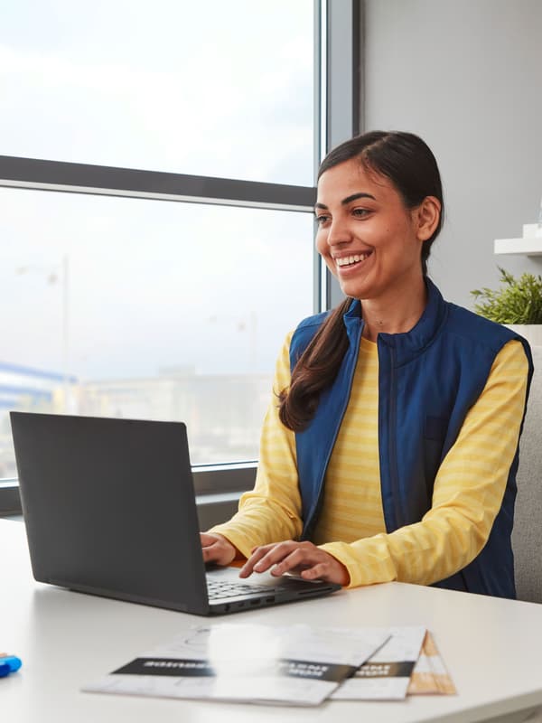 Une femme est assise à un bureau avec un ordinateur de bureau et un ordinateur portable.