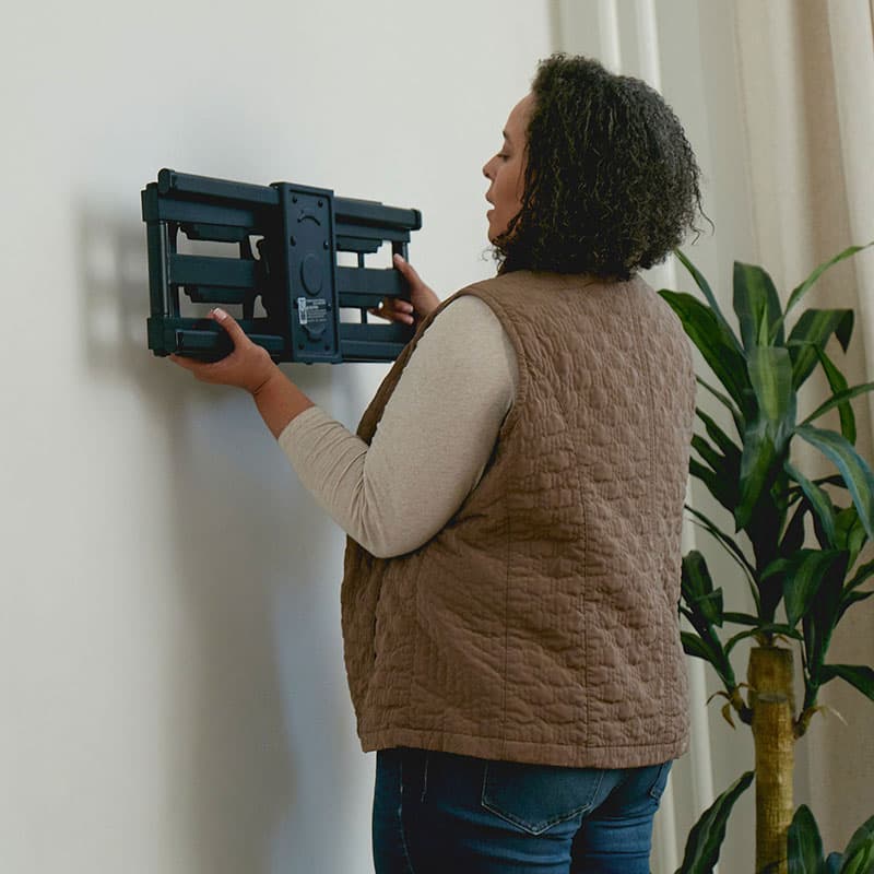 Une femme installe une étagère murale