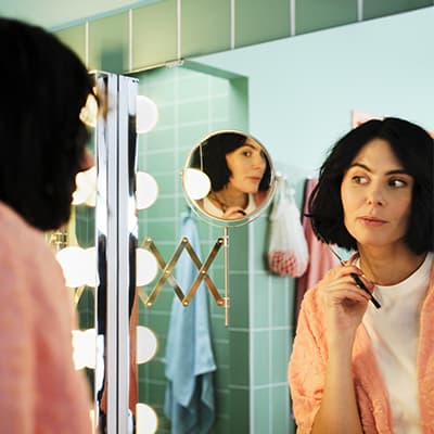 Une femme se coupe les pointes de cheveux en se regardant dans un miroir grossissant