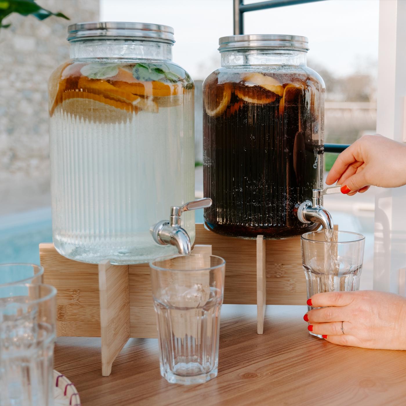Une femme se sert un verre d'une boisson dans une jarre.