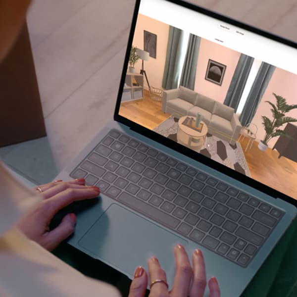 Une femme sur un ordinateur portable crée virtuellement un salon dans IKEA Kreativ
