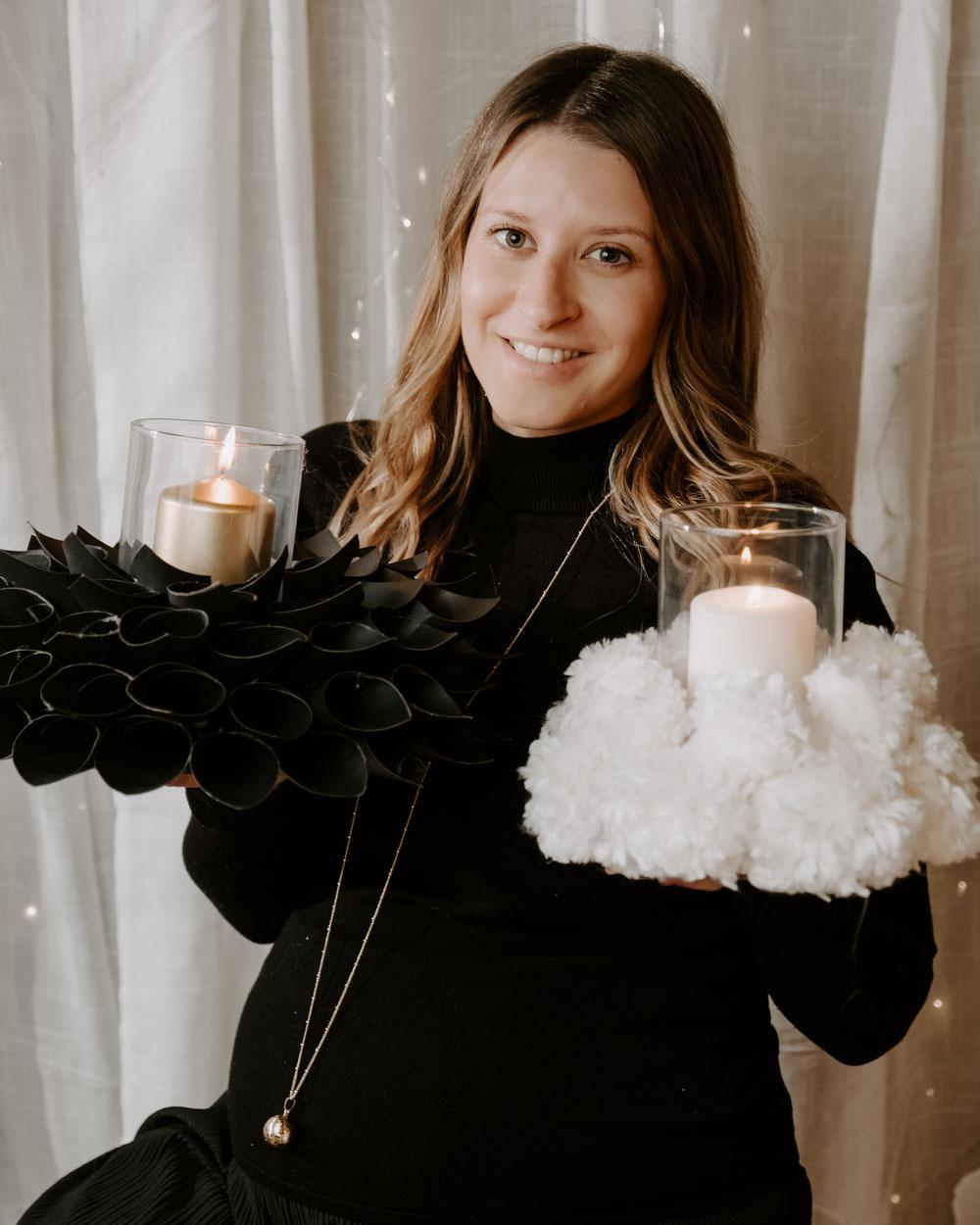 Une femme tient dans sa main de créations qu'elle a fait pour faire des centre de table avec bougies.