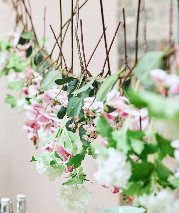 Une guirlande estivale fabriquée avec des fleurs artificielles roses et blanches suspendues à une corde à linge.