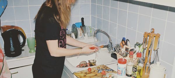 Une jeune femme fait la vaisselle dans une cuisine embourbée.