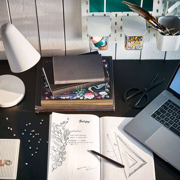 Une lampe de bureau FUBBLA blanche sur un bureau noir.