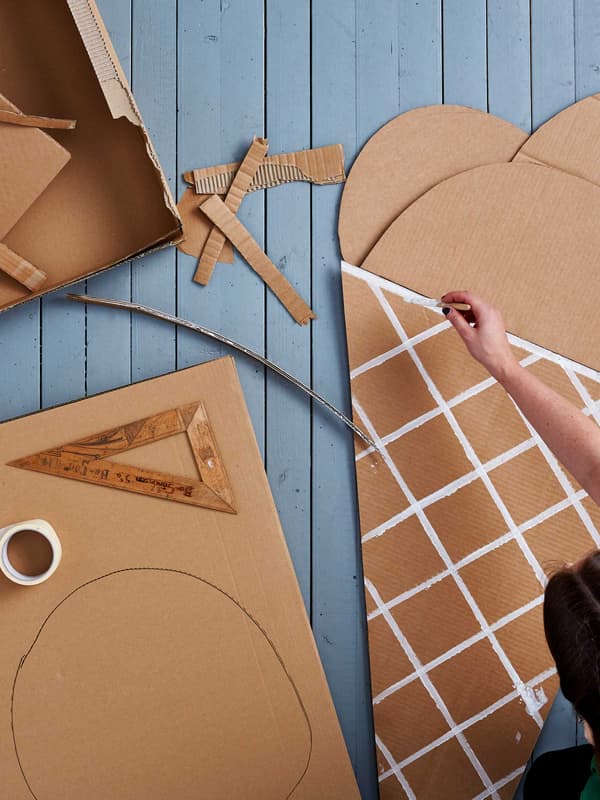 Une main peint un cornet de crème glacée sur un emballage de meuble IKEA en carton.
