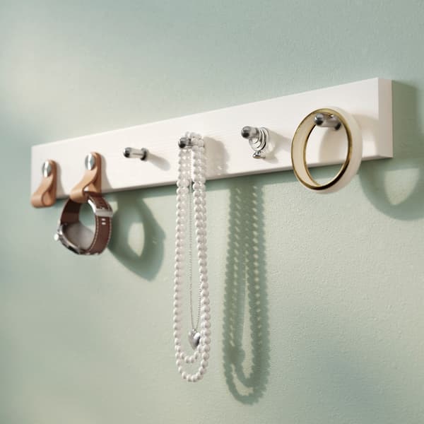 Une patère décorée avec des poignées en cuir IKEA ÖSTERNÄS et contenant une montre, des perles et du ruban adhésif.
