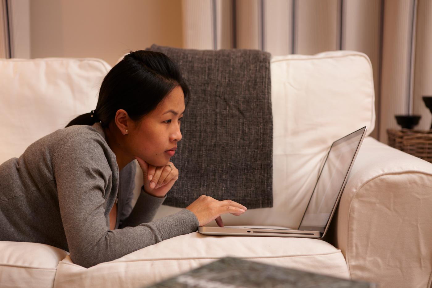 Une personne allongé sur son canapé en regardant son ordinateur