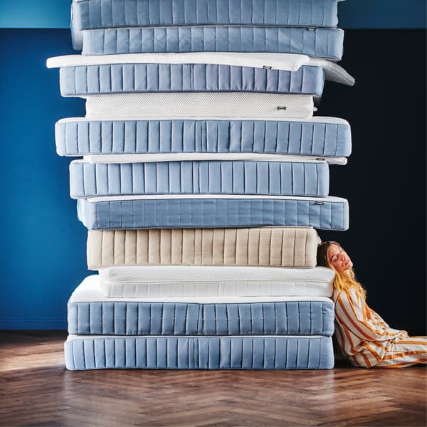 Une personne s'appuie contre une pile de sept matelas.