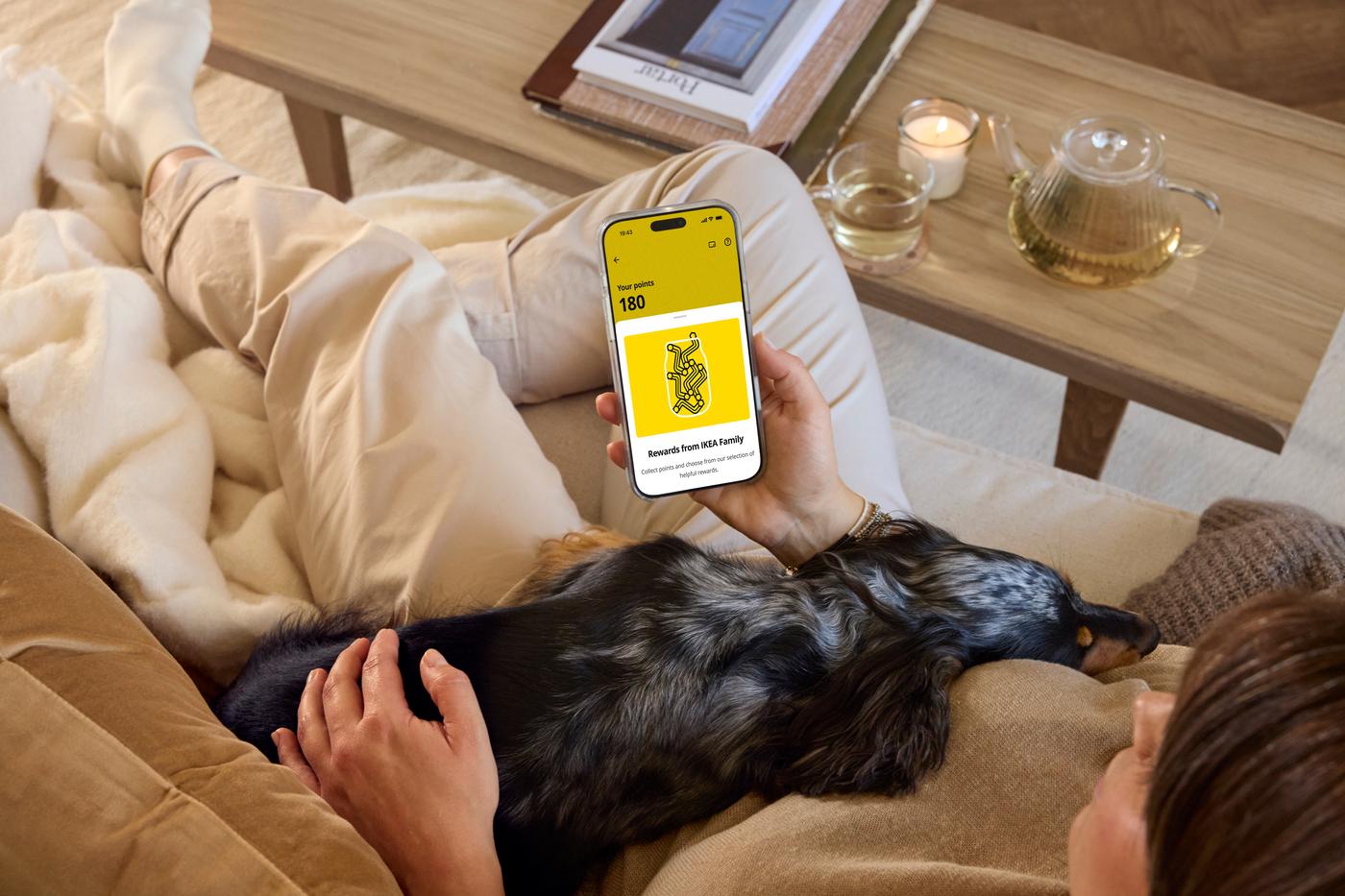 une personne sur un canapé avec un smartphone pour regarder ses points de fidélité IKEA Family