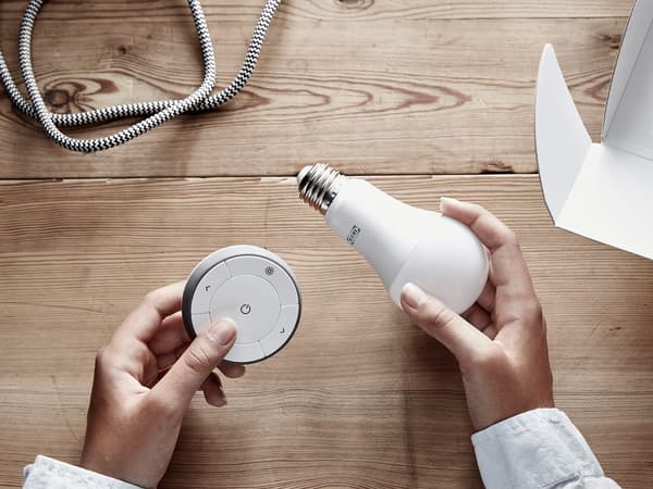 Une personne tient un ensemble gradateur comprenant une ampoule à DEL et une télécommande.