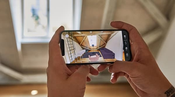 Une personne tient un smartphone et visualise une pièce vide meublée avec des produits IKEA en réalité augmentée.