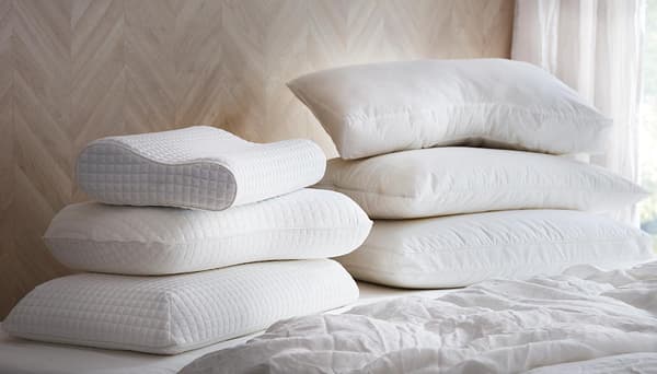 Une personne vêtue de jaune dormant sur le côté sur un oreiller ergonomique PRAKTVÄDD avec housse blanche, avec du linge de lit jaune.