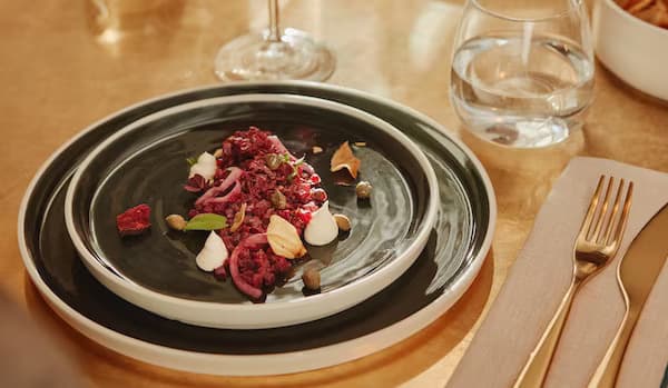 Une petite assiette noire avec un plat coloré dans une plus grand assiette noire