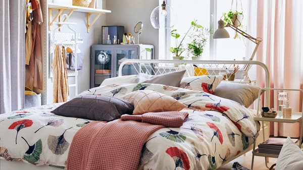 Une petite chambre avec un lit NESTTUN au milieu recouvert d’une housse de couette TOVSIPPA, avec du rangement et des tablettes le long des murs.
