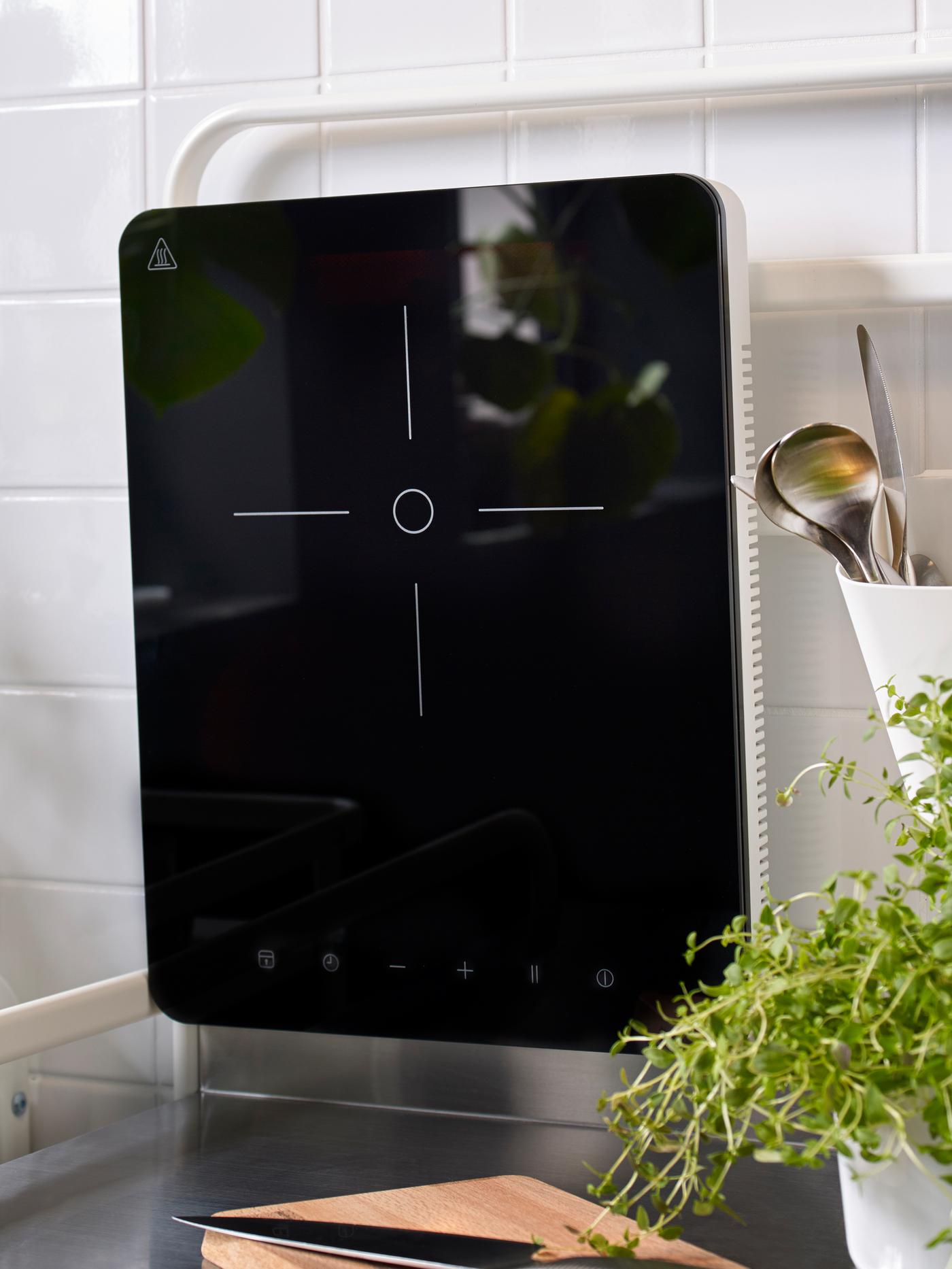 Une petite table de cuisson à induction mobile noire suspendue au mur.