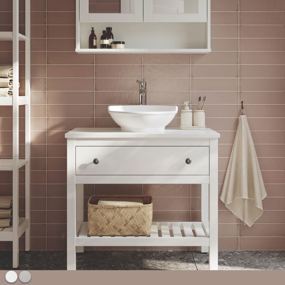 Une salle de bain carrelée rose pâle avec un meuble traditionnel blanc.