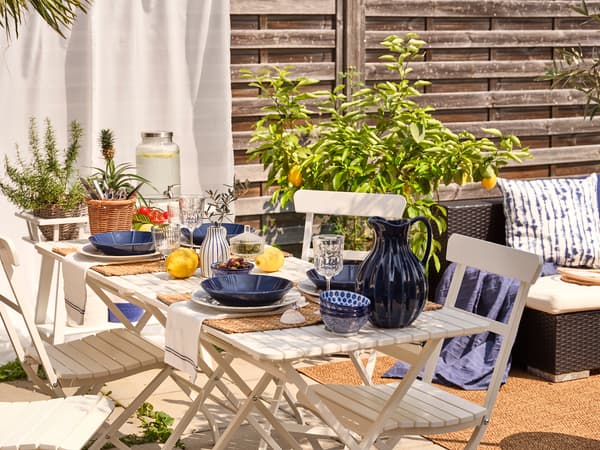 Une set de table et chaises d'extérieur beige avec des assiettes bleues disposées dessus.