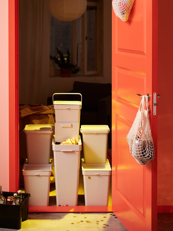Une station de recyclage faite de différentes poubelles HÅLLBAR installée dans l’entrée d’une chambre, la porte grande ouverte.