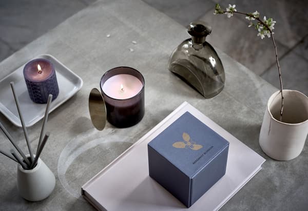 Une surface ornée d’un agencement symétrique de bougies parfumées, d’un gobelet en fleur et d’autres décorations dignes d’un spa.