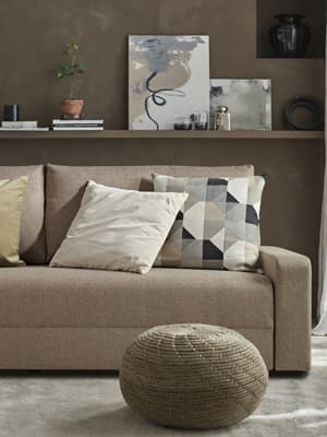 Une table basse noire se trouve devant un canapé-lit 2 places GRÄLVIKEN dans un salon aux couleurs terreuses. 