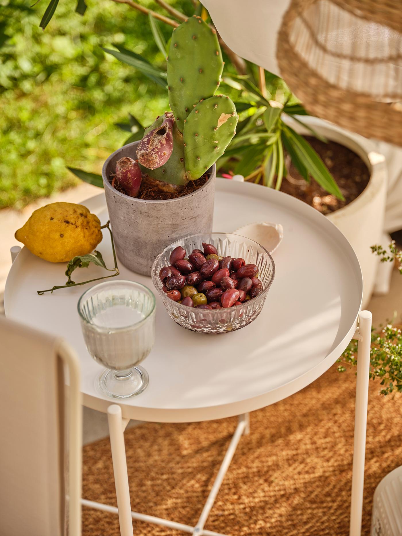 Une table d'appoint blanche avec des fruits et un jus posés dessus.