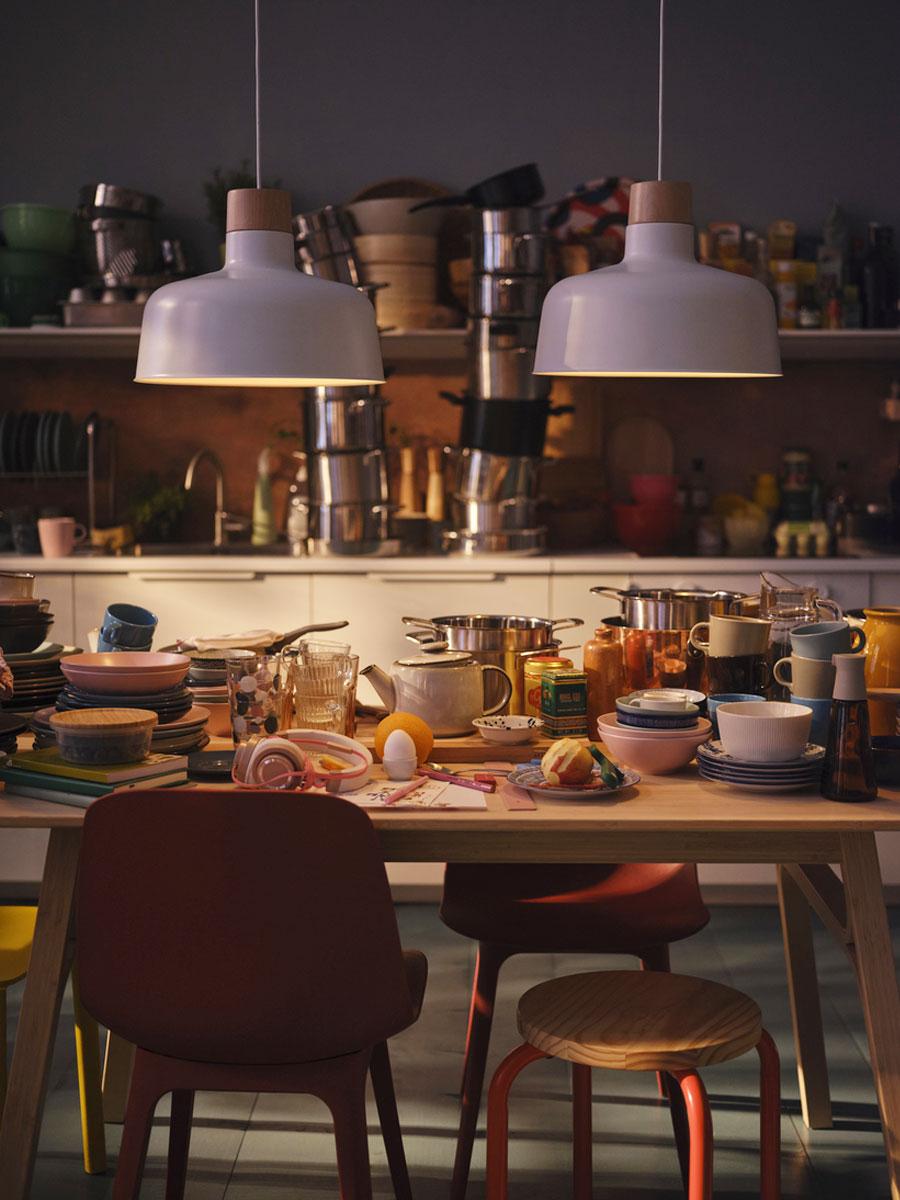 Une table de salle à manger dans la cuisine avec une multitude de vaisselle et ustensiles de cuisine mal rangés