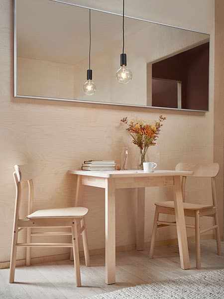 Une table de salle à manger NORRÅKER avec deux chaises RÖNNINGE sous un miroir HOVET.