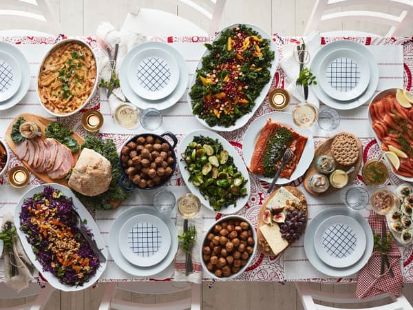 Une table des Fêtes pour six sur laquelle se trouvent des boulettes de viande, du jambon, du saumon et plus encore.