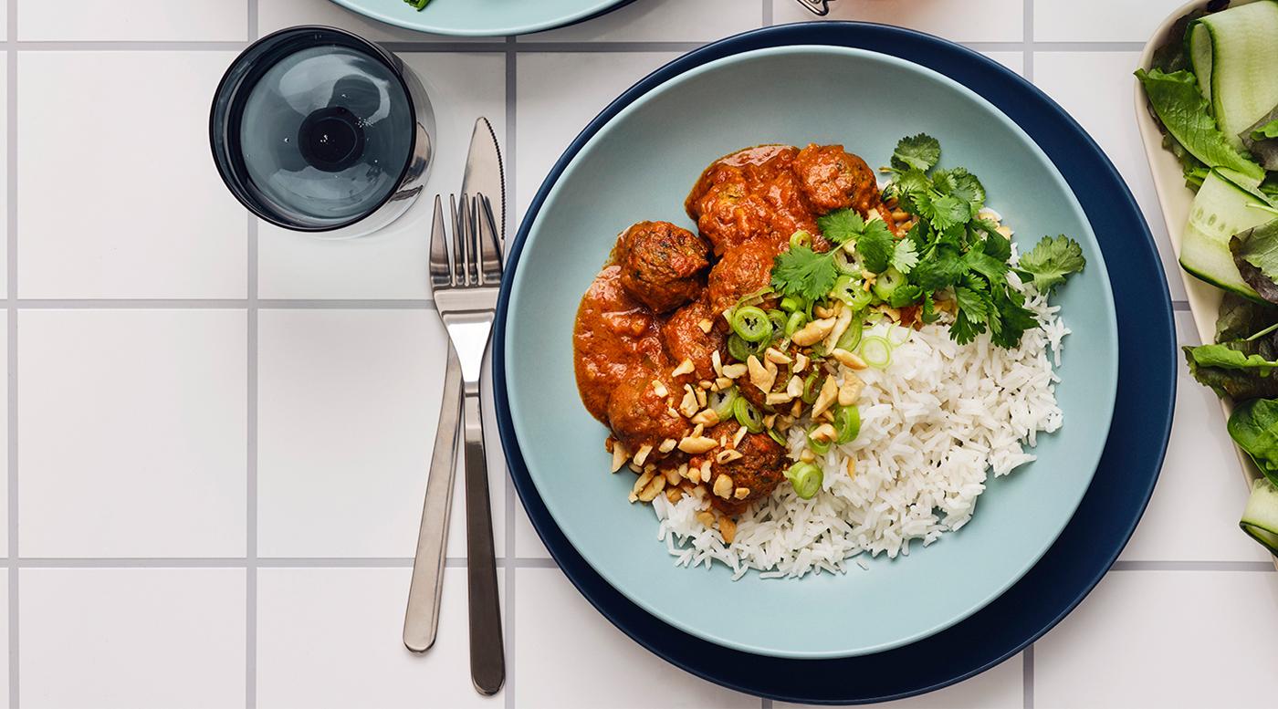Une table dressée sur laquelle repose un ragoût de boulettes végétariennes aux épices indiennes.