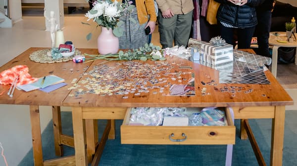 Une table est en exposition, avec plusieurs objets sur le dessus, comme un casse-tête, un vase, des décorations et du papier d’emballage.