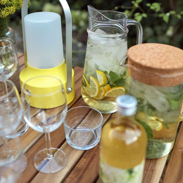 Une table extérieure avec des verres à vin et de l’eau citronnée dans un pichet.