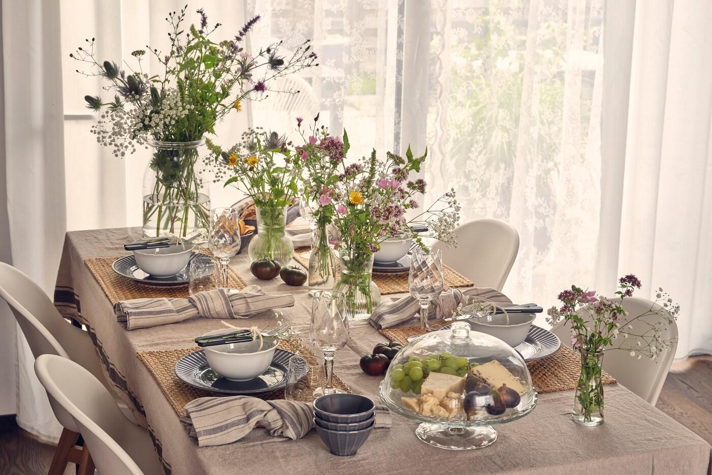 Une table festive aux couleurs claires et accueillantes, décorée de plusieurs bouquets de fleurs.