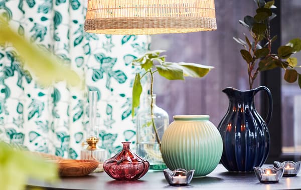 Une table subtilement décorée de petits vases et de bougies avec de petites feuilles vertes et des symboles du printemps.