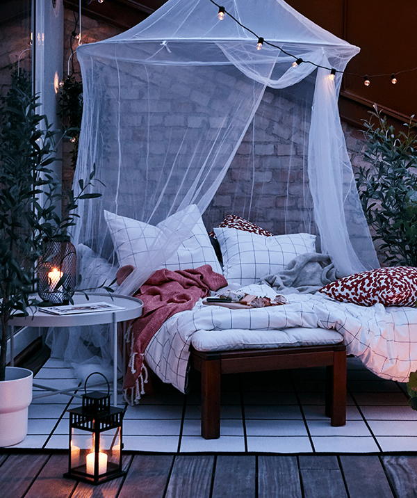 Une terrasse décorée d'un ciel transparent au dessus d'un canapé extérieur avec des lanternes et bougies