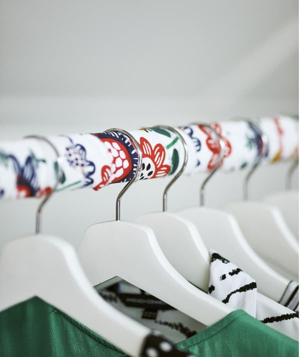 Une tringle à vêtements recouverte de tissu avec des cintres blancs.