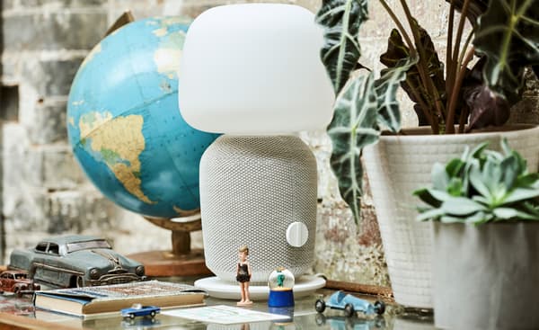 Une vitrine sur laquelle sont posés un globe terrestre, des plantes en pot, une lampe-haut-parleur blanche, des figurines, des petites voitures, des boules à neige et un livre.