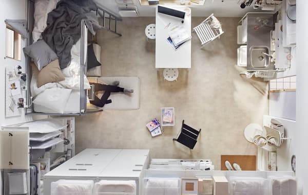 Une vue aérienne d'un espace de vie compact, incluant un lit, des garde-robes, une table à manger et une petite cuisine.