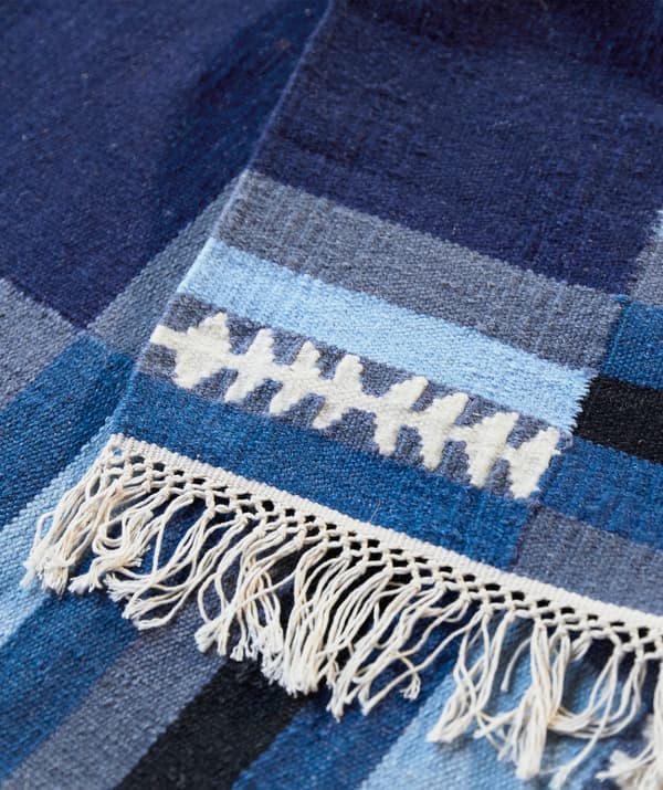 Unha alfombra azul con franxas en horizontal e orlas.