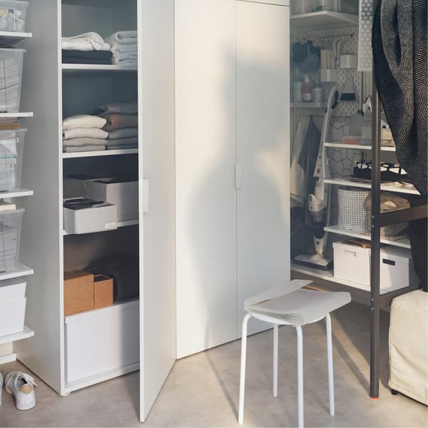 Unha área de almacenaxe repleta de caixas, estantes e unha unidade de almacenaxe IKEA PLATSA chea de roupa e caixas.