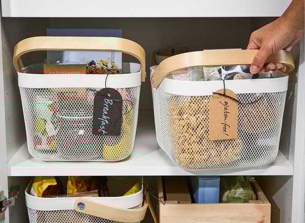 Unha cesta de reixa de aceiro IKEA RISATORP branca para organizar alimentos por tipos ou alérxenos.