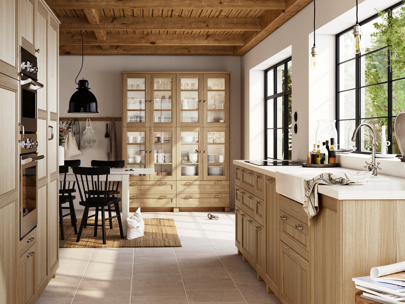 Unha cociña rústica con frontes en efecto carballo VEDHAMN, armarios de cociña, unha mesa con varias cadeiras e un vertedoiro HAVSEN en branco.