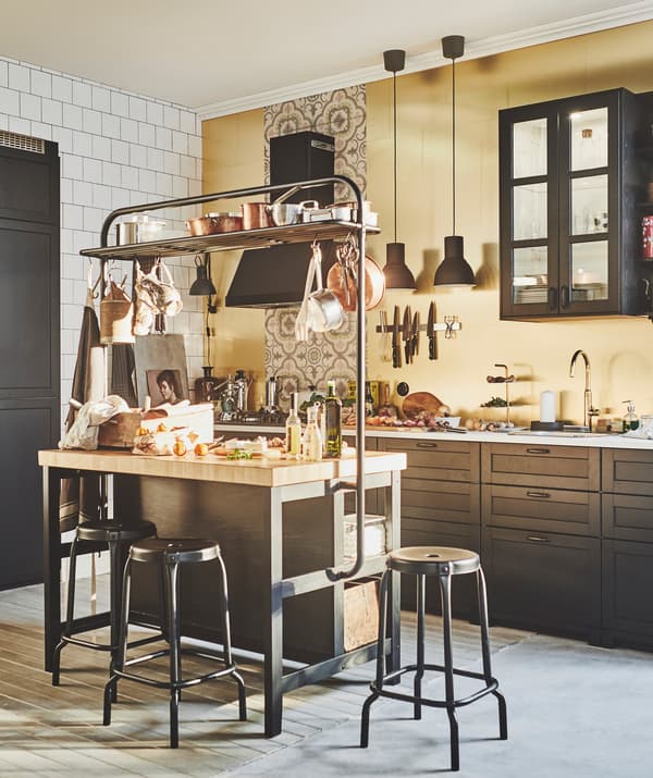Unha cociña, unha illa de cociña rodeada de tallos e paneis de cor bronce IKEA LYSEKIL.