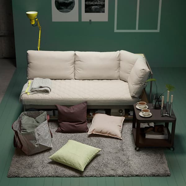 Unha escena cun deseño de sala cun sofá en cor crema, coxíns repartidos polo chan e unha mesa auxiliar.