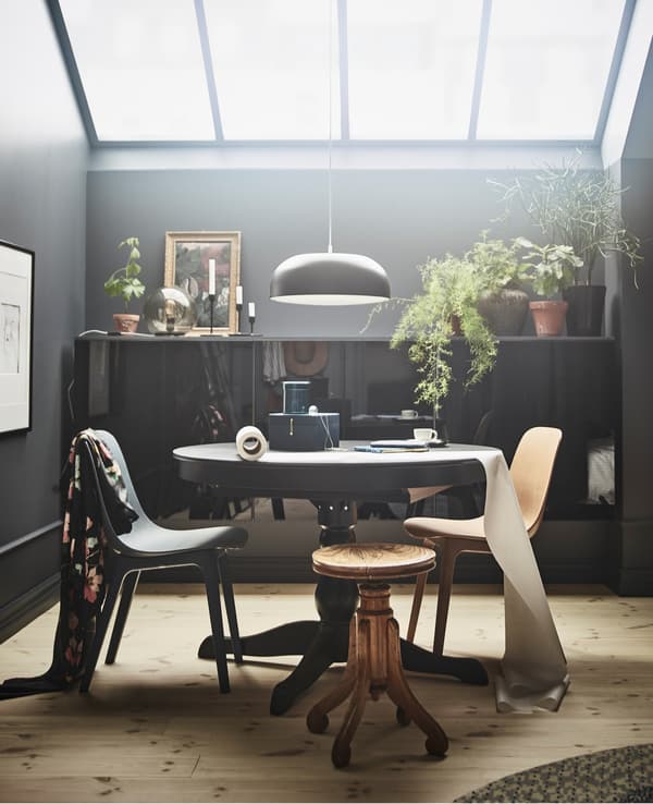 Unha mesa extensible INGATORP en negro crea un espazo para comer ou traballar neste dormitorio con claraboias.