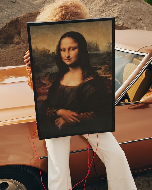 Unha modelo suxeita un cadro da Mona Lisa diante da cara.