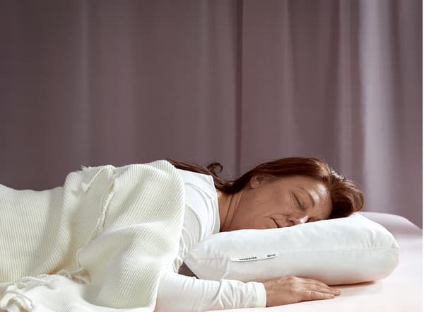 Unha muller nova dorme placidamente boca abaixo cunha almofada ergonómica IKEA SKOGSLÖK.