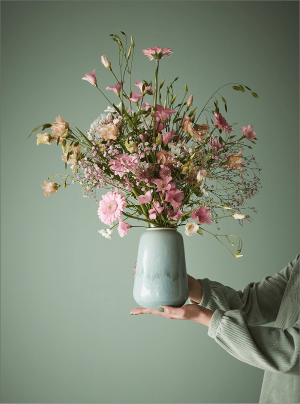 Unha muller sostén un floreiro con flores
