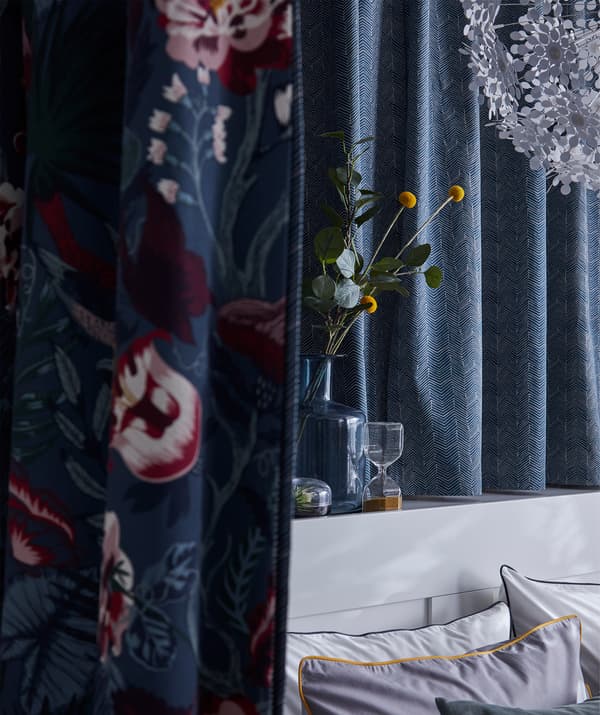 Unha parede forrada con tea IKEA ILDRID cun sutil estampado gráfico en azul e beixe.