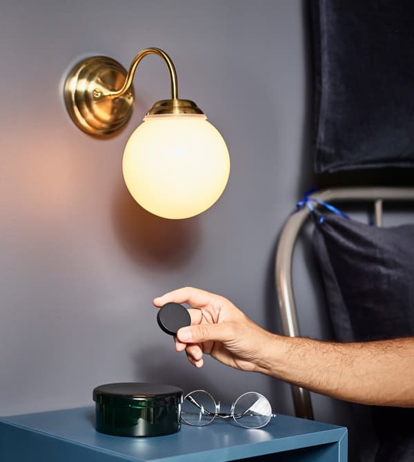 Unha persoa empregando un regulador de intensidade da luz TRÅDFRI comodamente dende a súa cama sen ter que levantarse.